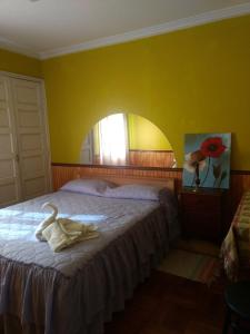 - une chambre avec un grand lit et un mur jaune dans l'établissement Hostal Valle Central San Fernando, Chile, à San Fernando