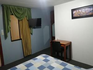 a room with a bed and a desk and a television at Hostal Pucará in Loja