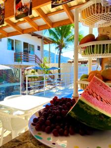 a plate of fruit on a table in front of a beach at Barreto Hospedagem in Caraguatatuba