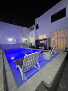 a swimming pool with two lawn chairs next to it at Departamento La Punta C - Piscina - Zona parrilla in Lima