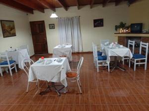uma sala com mesas e cadeiras com toalha de mesa branca em Akimekedo em Mendoza