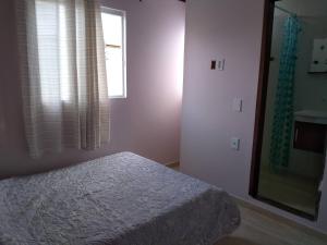 a bedroom with a bed and a window and a mirror at Casa do Sossego Guarajuba Barra do Jacuípe in Camaçari