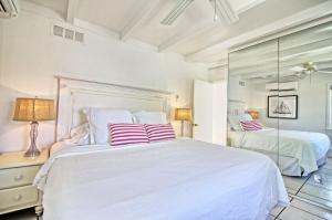 a white bedroom with two beds and a mirror at Gulfside Resort Unit 9 in St. Pete Beach