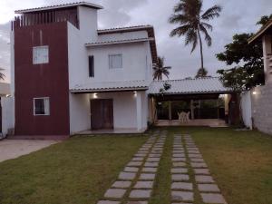 uma casa com um jardim de relva em frente em Casa do Sossego Guarajuba Barra do Jacuípe em Camaçari