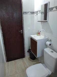 a bathroom with a toilet and a sink and a door at Casa do Sossego Guarajuba Barra do Jacuípe in Camaçari