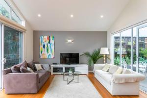 uma sala de estar com dois sofás e uma televisão em Beach House Close to Manly em Sydney