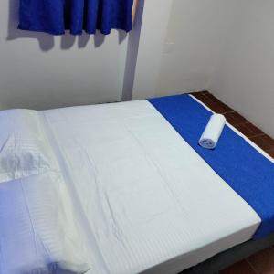 Una cama con sábanas azules y blancas y un rollo. en Hotel la Isabela By Marbar, en Villeta