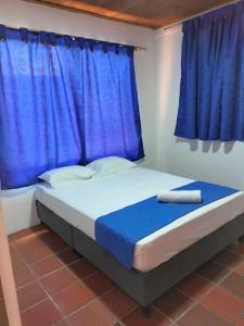 Cama en habitación con ventana azul en Hotel la Isabela By Marbar, en Villeta