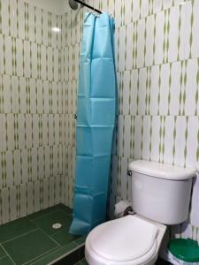 baño con aseo y cortina de ducha azul en Hotel la Isabela By Marbar, en Villeta