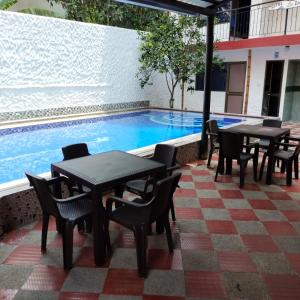 un patio con mesas y sillas junto a una piscina en Hotel la Isabela By Marbar, en Villeta