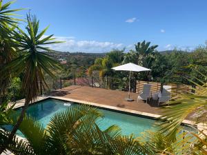 a swimming pool with two chairs and an umbrella at Gold Coast uninterrupted uphill view & big pool in Gold Coast