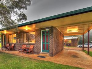 a brick house with a red door and chairs on a patio at Bunya Mountains Tavern 