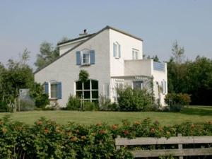 a white house with blue windows and a yard at Chalet in Texel by Dunes and Water in De Cocksdorp