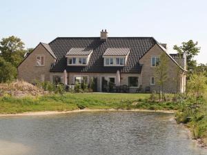 a large house with a river in front of it at Villa in Texel near De Krim Holiday Park in De Cocksdorp