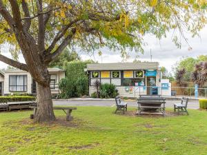 a park with benches and a tree and a gas station at NRMA Bairnsdale Riverside Holiday Park in Bairnsdale