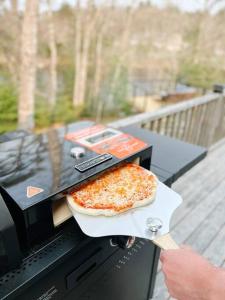 a person is holding a pizza on a grill at Morning Lane Cottage in Mill Village