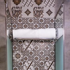 a bed with white sheets and a patterned wall at Malyabhara Hotel - formerly Ibis Malioboro in Yogyakarta