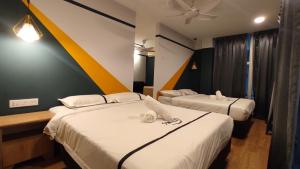 two beds in a hotel room with towels on them at Smile Hotel C180 Cheras Selatan in Cheras