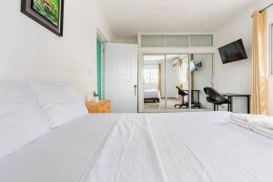 1 dormitorio blanco con 1 cama blanca y 1 silla en SDQ airport & Samana bus near Bamboo, en Santo Domingo