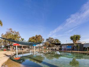 a swimming pool with a hammock in front of a building at NRMA Yarrawonga Mulwala Holiday Park in Mulwala
