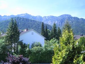 ein weißes Haus inmitten von Bäumen und Bergen in der Unterkunft Ferienwohnung Mautweg in Bad Reichenhall