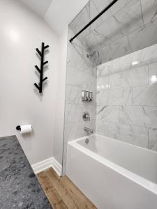 a white bath tub in a bathroom with marble walls at The Cozy Cove Modern King-Bedroom Full Apartment in St. Catharines