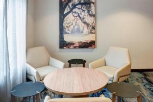 uma sala de espera com uma mesa e cadeiras e um quadro em Fairfield Inn & Suites Wilmington Wrightsville Beach em Wilmington