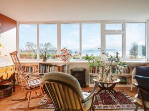 - un salon avec une table, des chaises et des fenêtres dans l'établissement Strathcashel Cottage, à Rowardennan