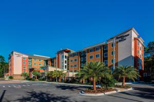 an apartment building with palm trees in a parking lot at Residence Inn by Marriott Jacksonville South Bartram Park in Jacksonville