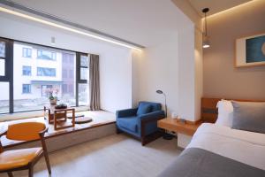a bedroom with a bed and a chair and a window at Jiushui Heyuan Art Design Hotel in Qingdao
