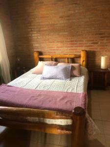 El Nogalito Mina Clavero في Arroyo de Los Patos: سرير خشبي في غرفة بجدار من الطوب