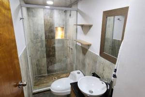 een badkamer met een douche, een wastafel en een toilet bij Terranova, apto en el Salvador in Medellín