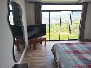 1 dormitorio con TV y ventana grande en habitación en Villa Tina, en Santa Rosa de Cabal