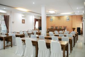 una sala conferenze con tavoli in legno e sedie bianche di WISMA KUSUMA HOTEL 