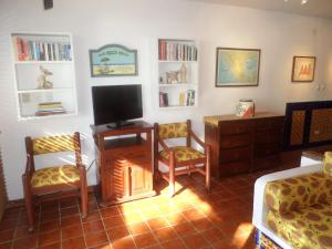 a living room with a tv and two chairs and a fireplace at Humble, Right On The Beach in Akumal