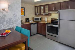 a kitchen with a table and a white refrigerator at Residence Inn by Marriott New Orleans Metairie in Metairie