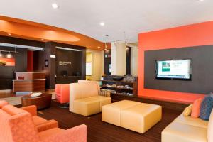 a lobby with orange furniture and a flat screen tv at Courtyard by Marriott Peoria in Peoria