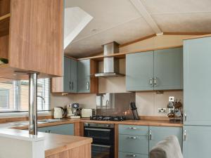 a kitchen with blue cabinets and a stove top oven at Lodge 69 in Stonham Aspall