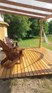 a wooden deck with two chairs and a table at Casa cerca del lago in Lago Puelo