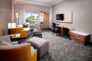 ein Hotelzimmer mit einem Schreibtisch, einem Bett und einem Sofa in der Unterkunft Courtyard by Marriott Palm Beach Jupiter in Jupiter