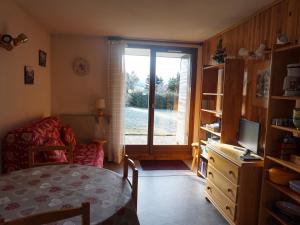 a living room with a table and a chair and a window at Studio Autrans, 1 pièce, 4 personnes - FR-1-737-53 in Autrans