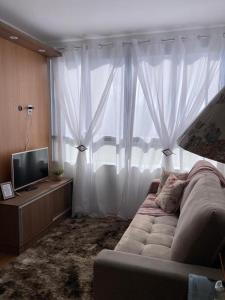 a living room with a couch and a large window at Melhor Ap Poços de Caldas in Poços de Caldas