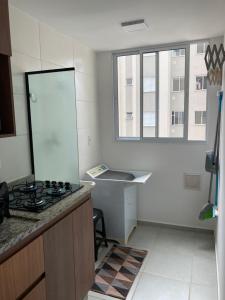 a kitchen with a stove and a sink and a window at Melhor Ap Poços de Caldas in Poços de Caldas