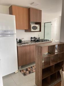 uma cozinha com um frigorífico branco e armários de madeira em Melhor Ap Poços de Caldas em Poços de Caldas