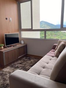 a living room with a couch and a flat screen tv at Melhor Ap Poços de Caldas in Poços de Caldas