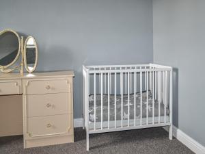 a baby crib with a mirror and a dresser at The Old School in Cleethorpes