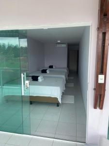 1 dormitorio con 2 camas y pared de cristal en Maragogimeucaribe01, en Maragogi