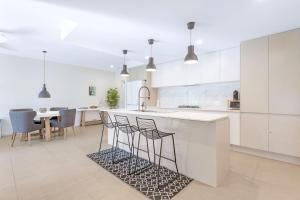 Una cocina con gabinetes blancos y una encimera con taburetes. en Le Maison at the Beach, en Huskisson 4 fotos más