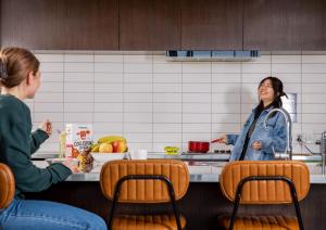 two women sitting at a counter in a kitchen at LyLo Christchurch - Formerly Jucy Snooze Christchurch in Christchurch