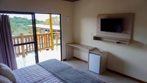 una camera con letto, TV e balcone di POUSADA KALUKA a Bezerros